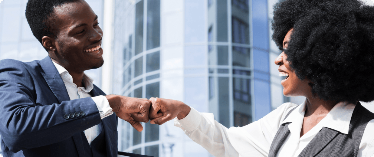 Two colleagues fist-bumping outside an office building